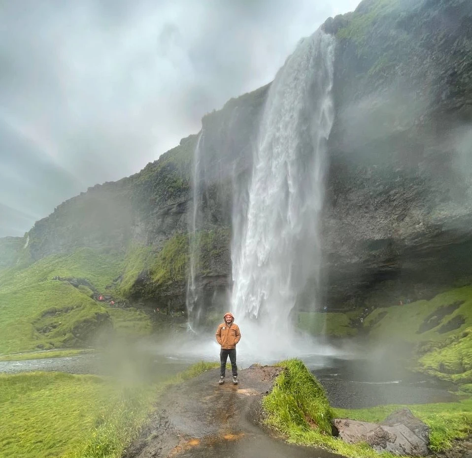 Iceland vacationer in raincoat at a remote waterfall after a hike