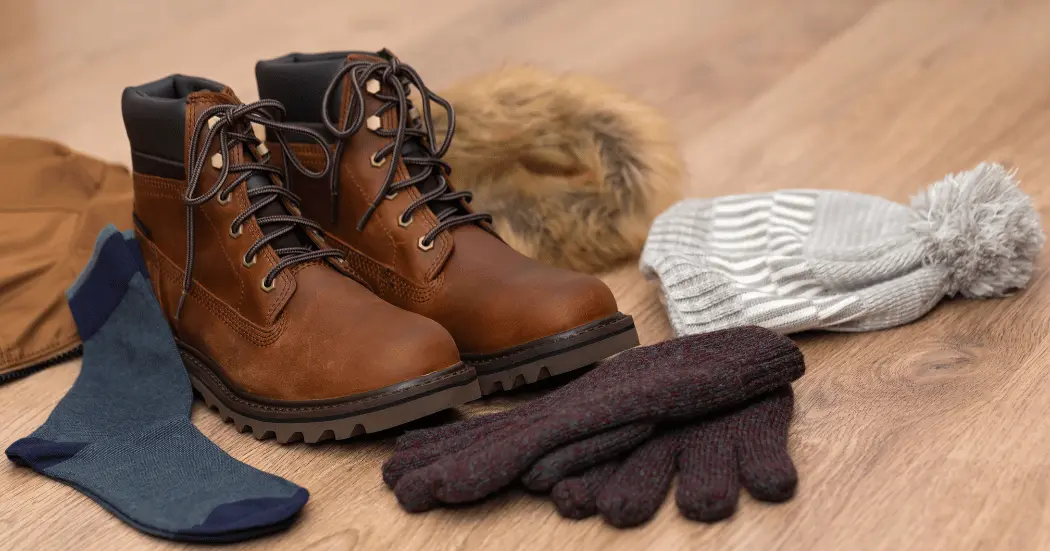 A variety of cold weather accessories: A beanie, gloves, wool socks, and winter boots