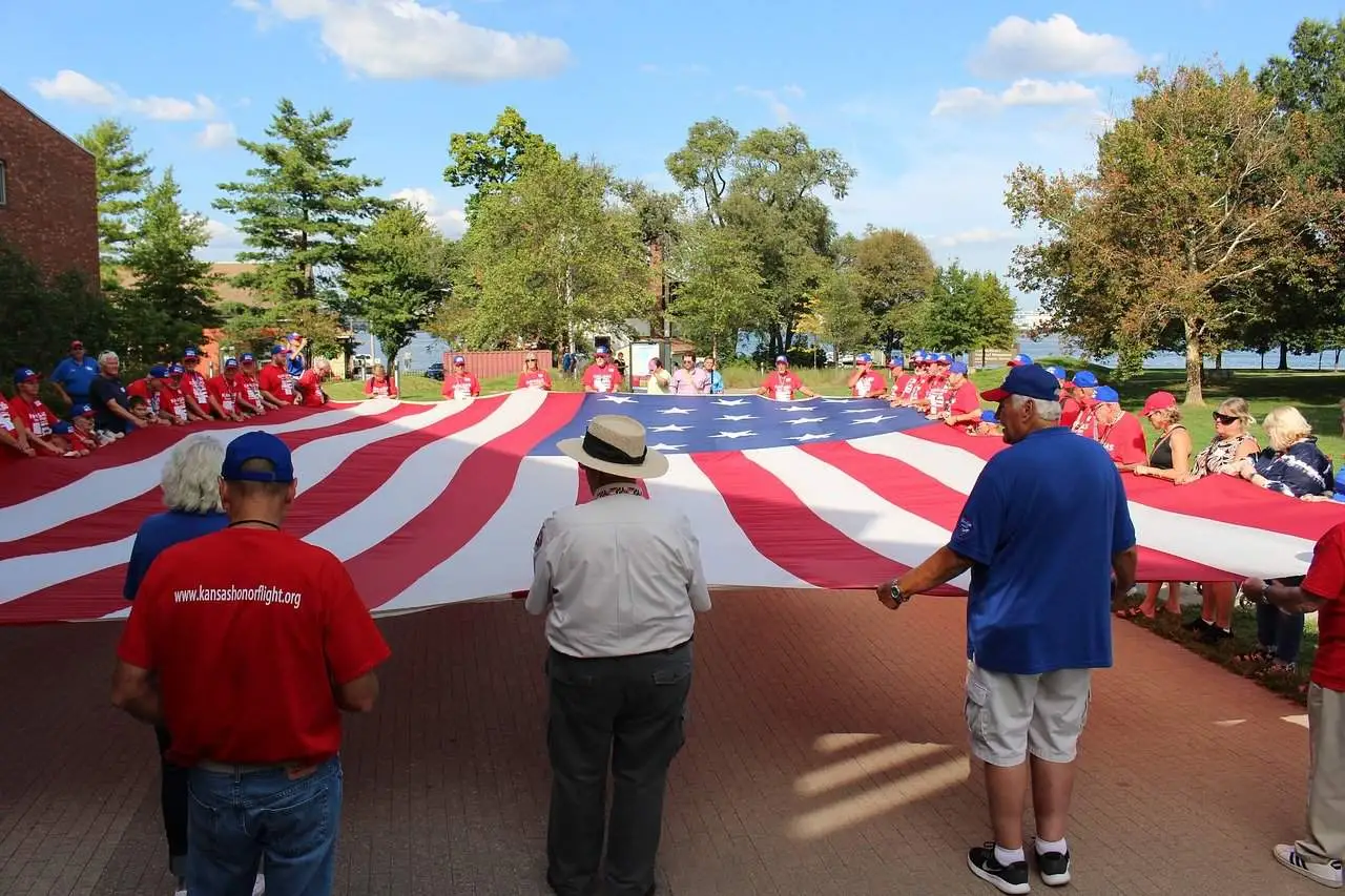 dozens of people holding the edges of a very large American flag in Kansas