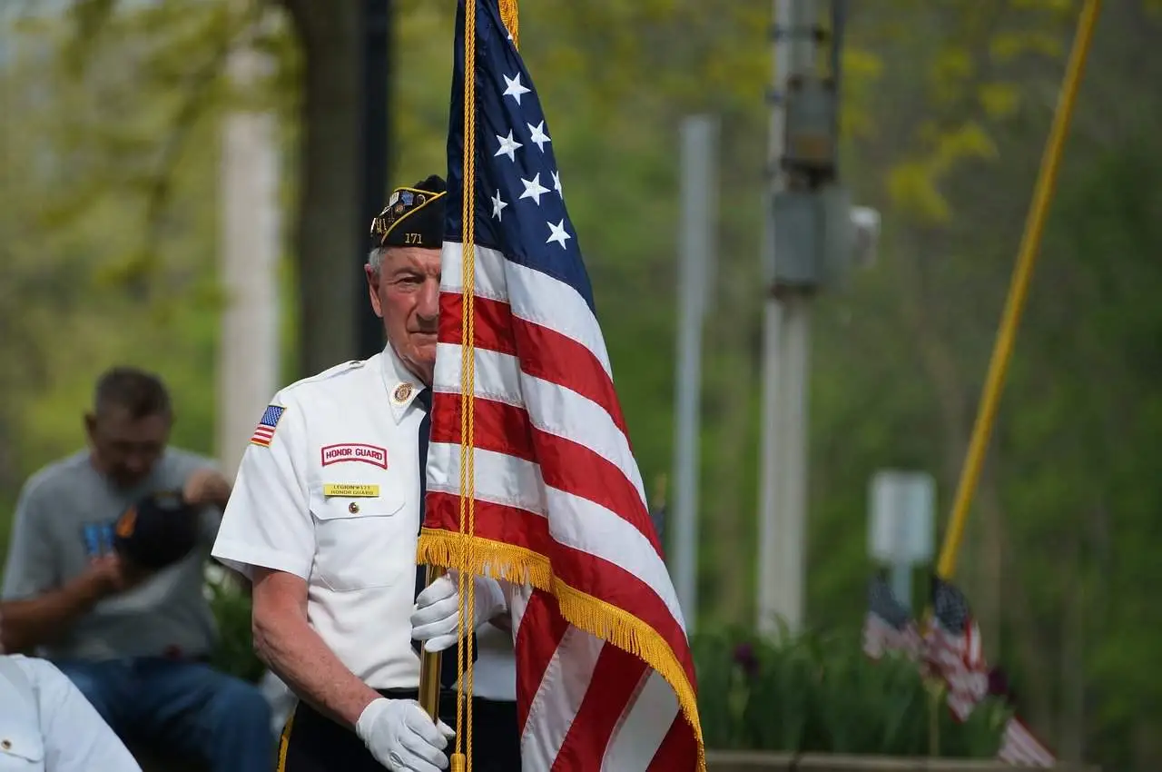 military veteran at attention with American flag
